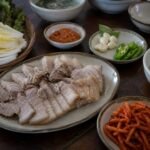 Korean bossam pork belly with napa cabbage, radish salad, garlic, chile, and ssamjang.