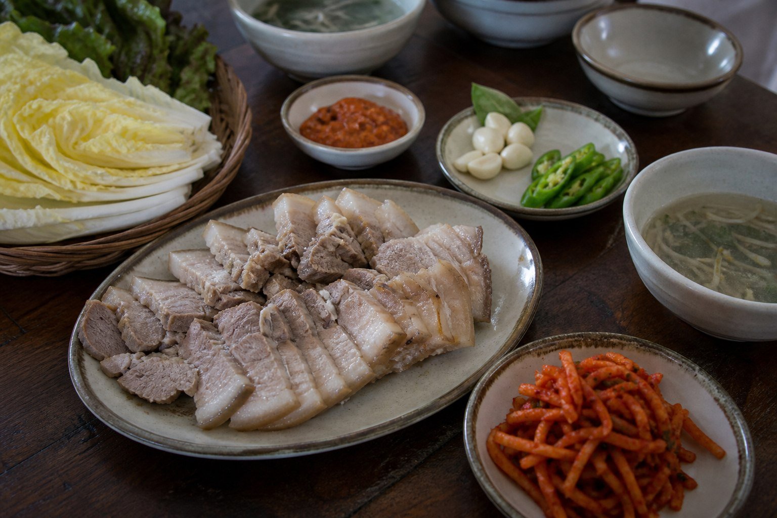 Korean bossam pork belly with napa cabbage, radish salad, garlic, chile, and ssamjang.