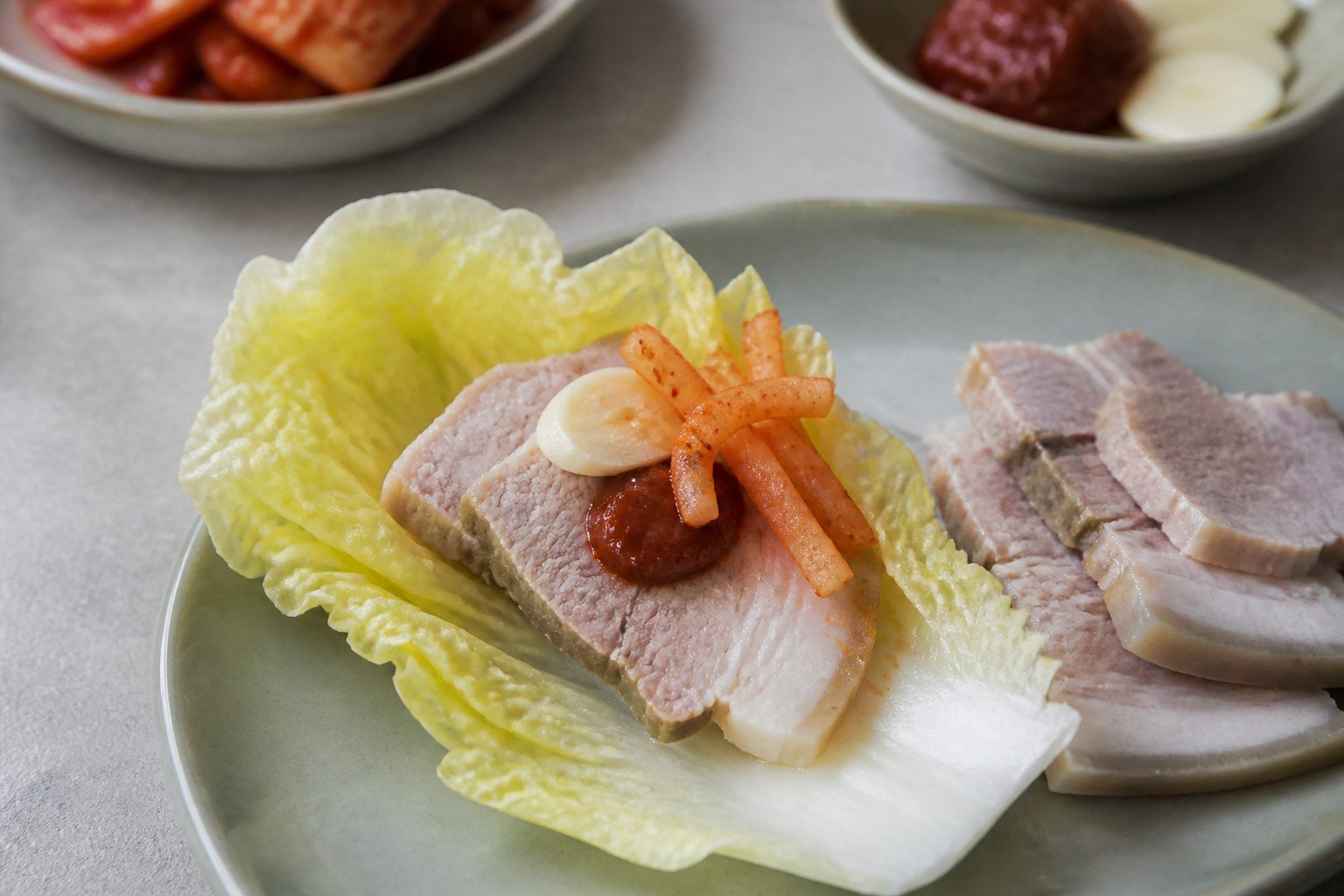 A napa cabbage bossam wrap with pork belly, ssamjang, garlic, and spicy radish.