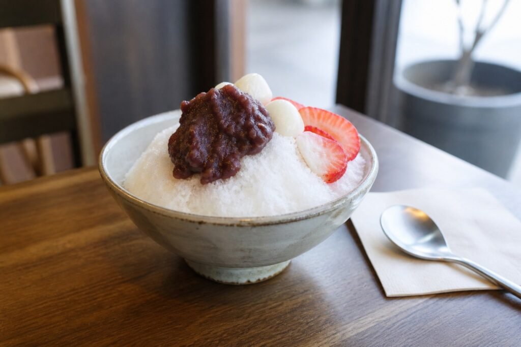 Korean patbingsu with fine milk ice, sweet red bean paste, rice cakes, and strawberries.