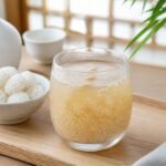 A chilled glass of Korean Sikhye sweet rice punch with rice grains and pine nuts.