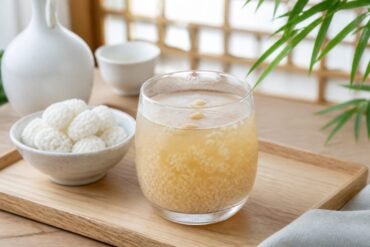 A chilled glass of Korean Sikhye sweet rice punch with rice grains and pine nuts.