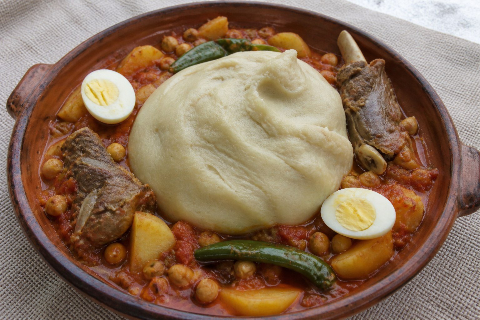 Libyan bazin with tomato lamb stew, potatoes, chickpeas, eggs, and green chiles.