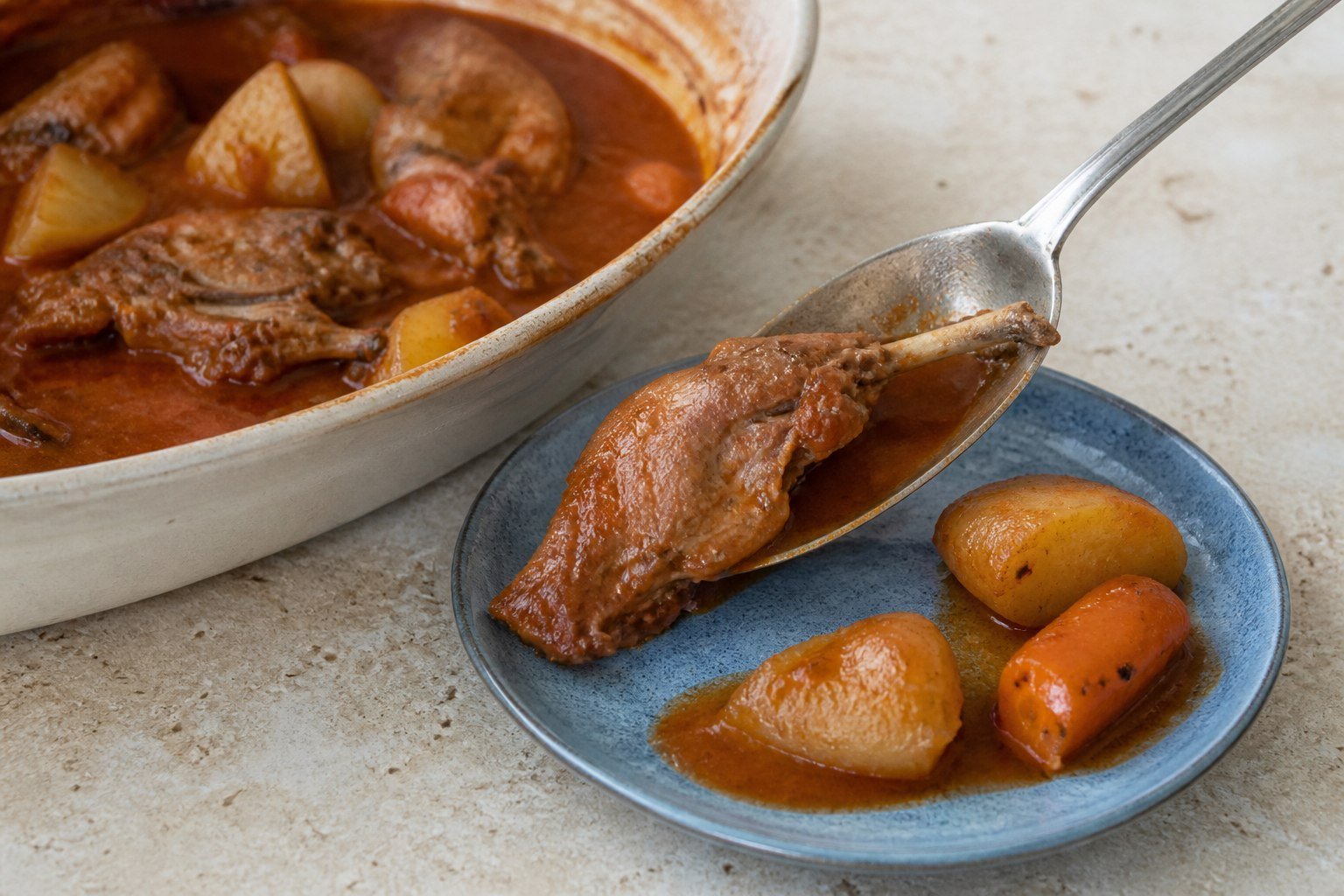 A natural bone-in rabbit leg from Maltese stuffat tal-fenek being served with potatoes and carrots.