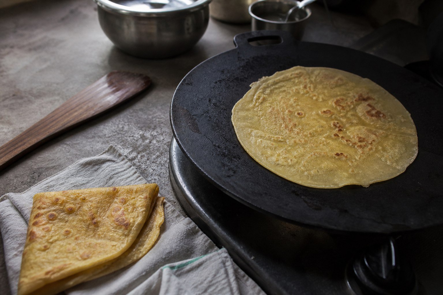 A thin Mauritian dholl puri cooking on a cast-iron tawa.