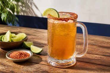 Chilled Mexican michelada with lime and a red chile-salt rim.