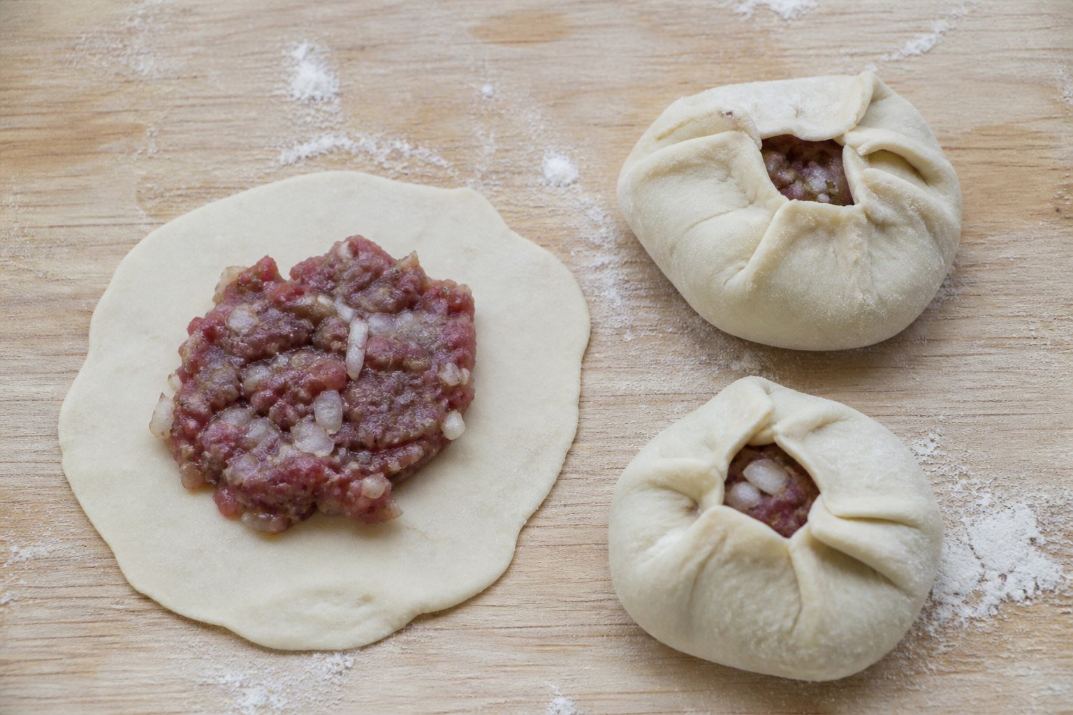 Mongolian buuz wrappers, meat filling, and two hand-pleated dumplings.