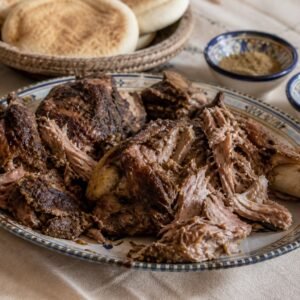 Moroccan mechoui lamb torn into large tender pieces and served with bread, cumin, and salt.