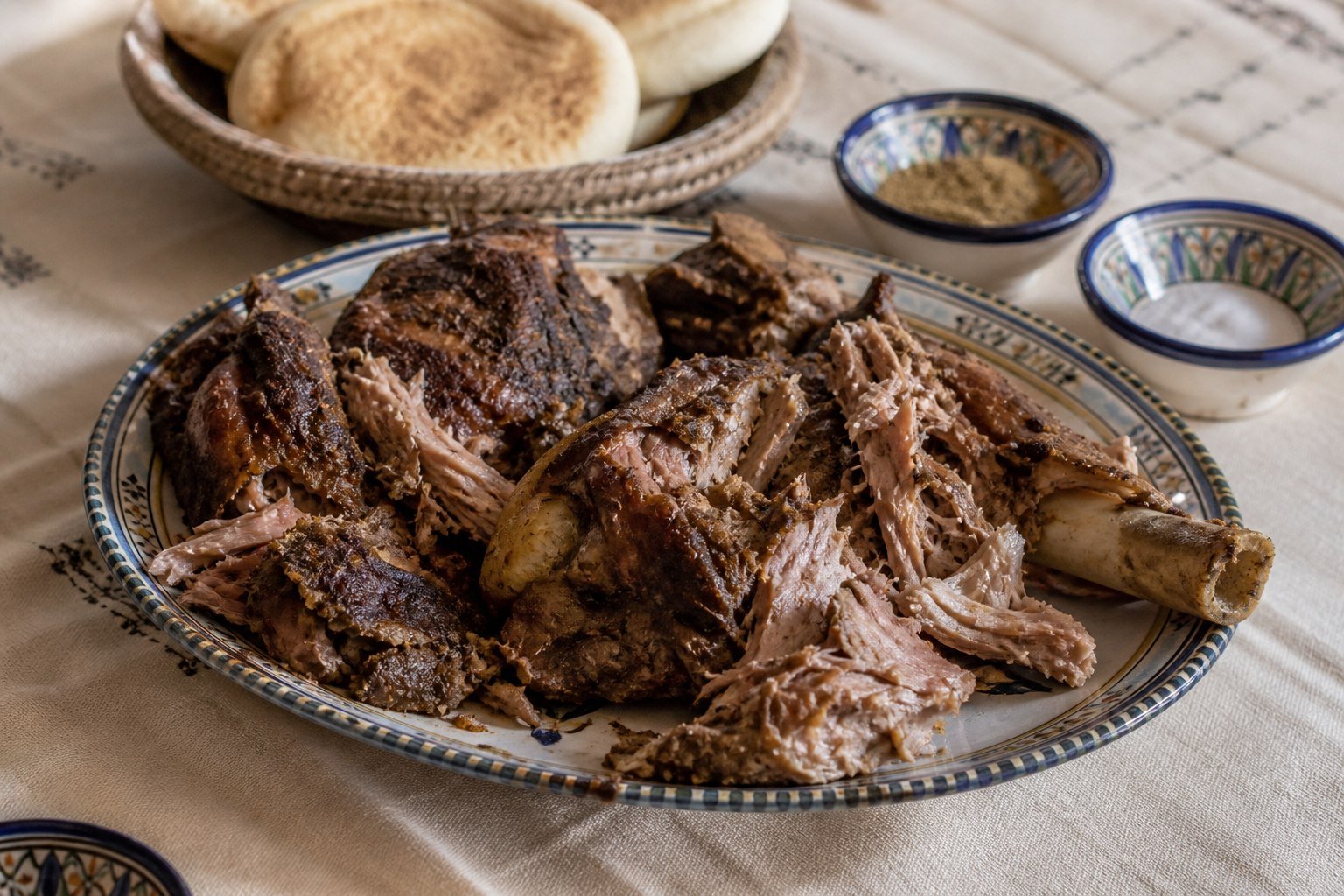 Moroccan mechoui lamb torn into large tender pieces and served with bread, cumin, and salt.