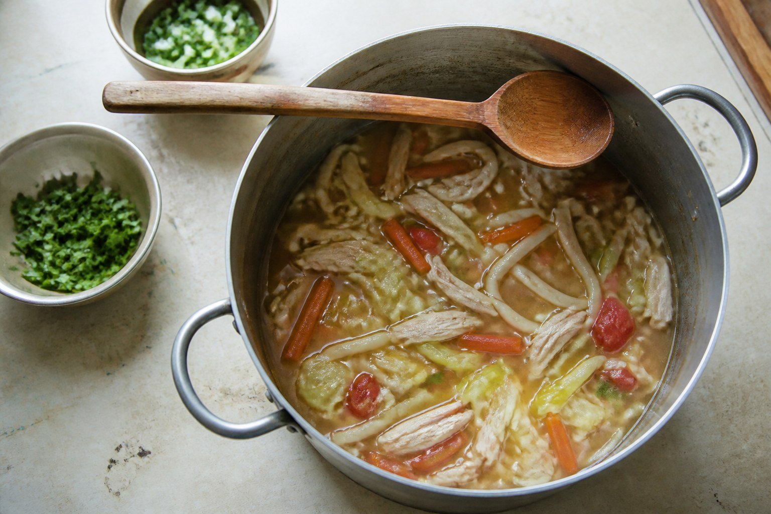 Chicken thukpa simmering with noodles and vegetables in a cooking pot.