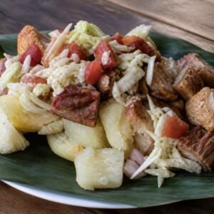 Nicaraguan vigorón with boiled yuca, chicharrón, and cabbage curtido on a banana leaf.