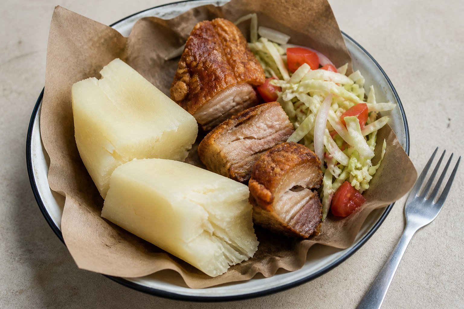 Vigorón served in a paper-lined bowl with yuca, pork belly, and cabbage salad.