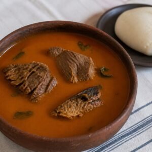Nigerian banga soup with beef, smoked fish, scent leaf, and a serving of white starch.