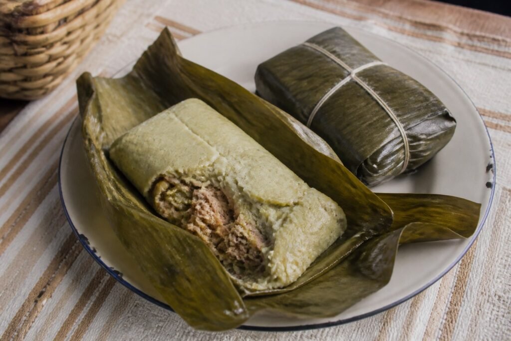 Puerto Rican pastel unwrapped on a banana leaf beside a tied parcel.