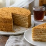 Russian medovik honey layer cake with a slice removed and black tea nearby.