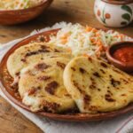 Golden Salvadoran pupusas served with curtido and tomato salsa.