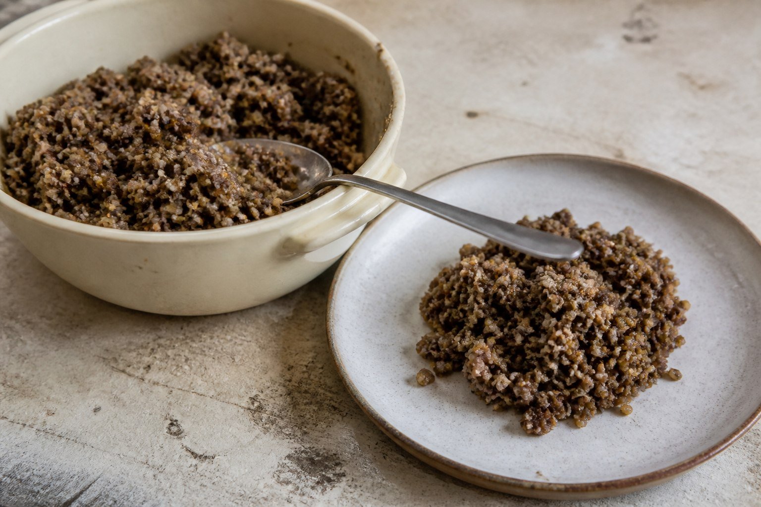 Coarse Scottish haggis being spooned from a pudding basin onto a plate.