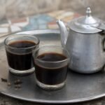 Senegalese Cafe Touba spiced coffee served in small glasses with a metal pot.