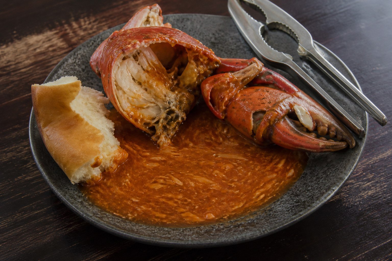 Cracked Singapore chili crab served with sauce, mantou, and a shell cracker.