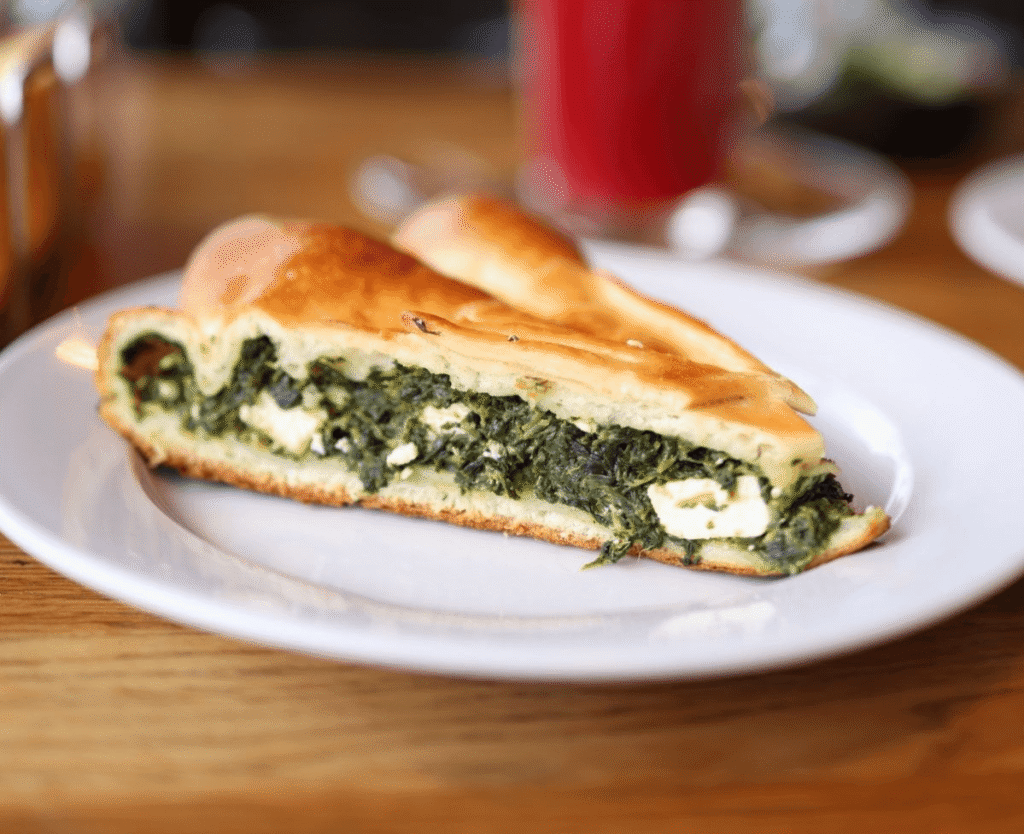 Close-up Greek spanakopita showing flaky phyllo layers and spinach feta filling.