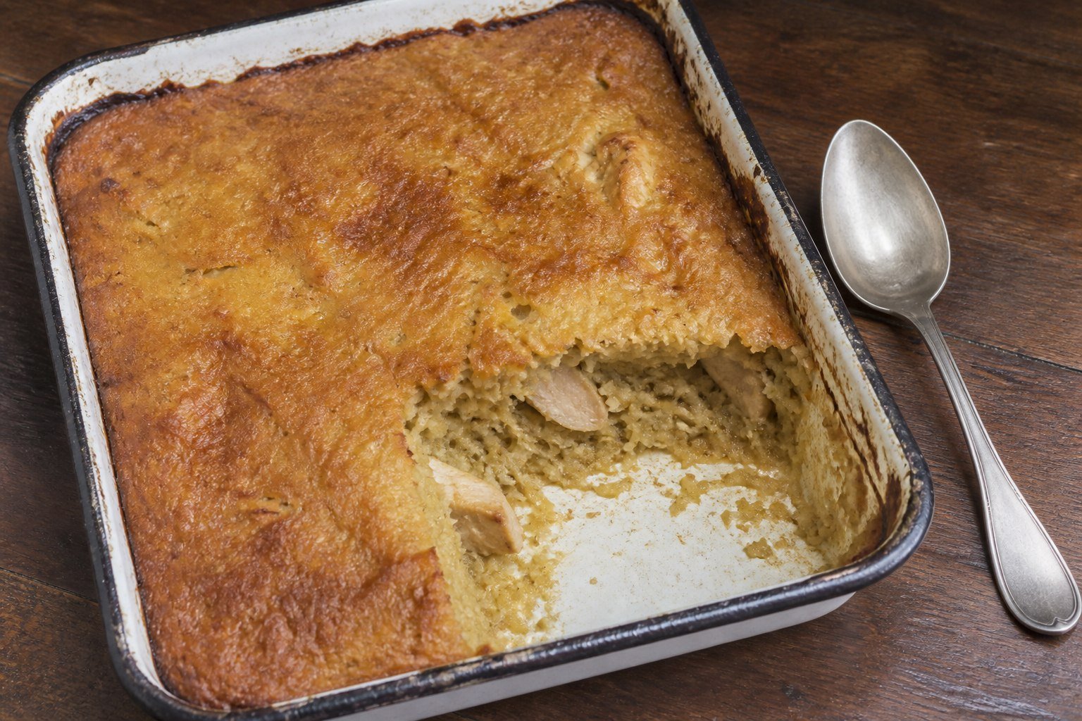 Surinamese pom in an enamel baking dish with one portion removed.