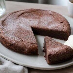 Swedish kladdkaka chocolate cake with a dense fudgy center and whipped cream.