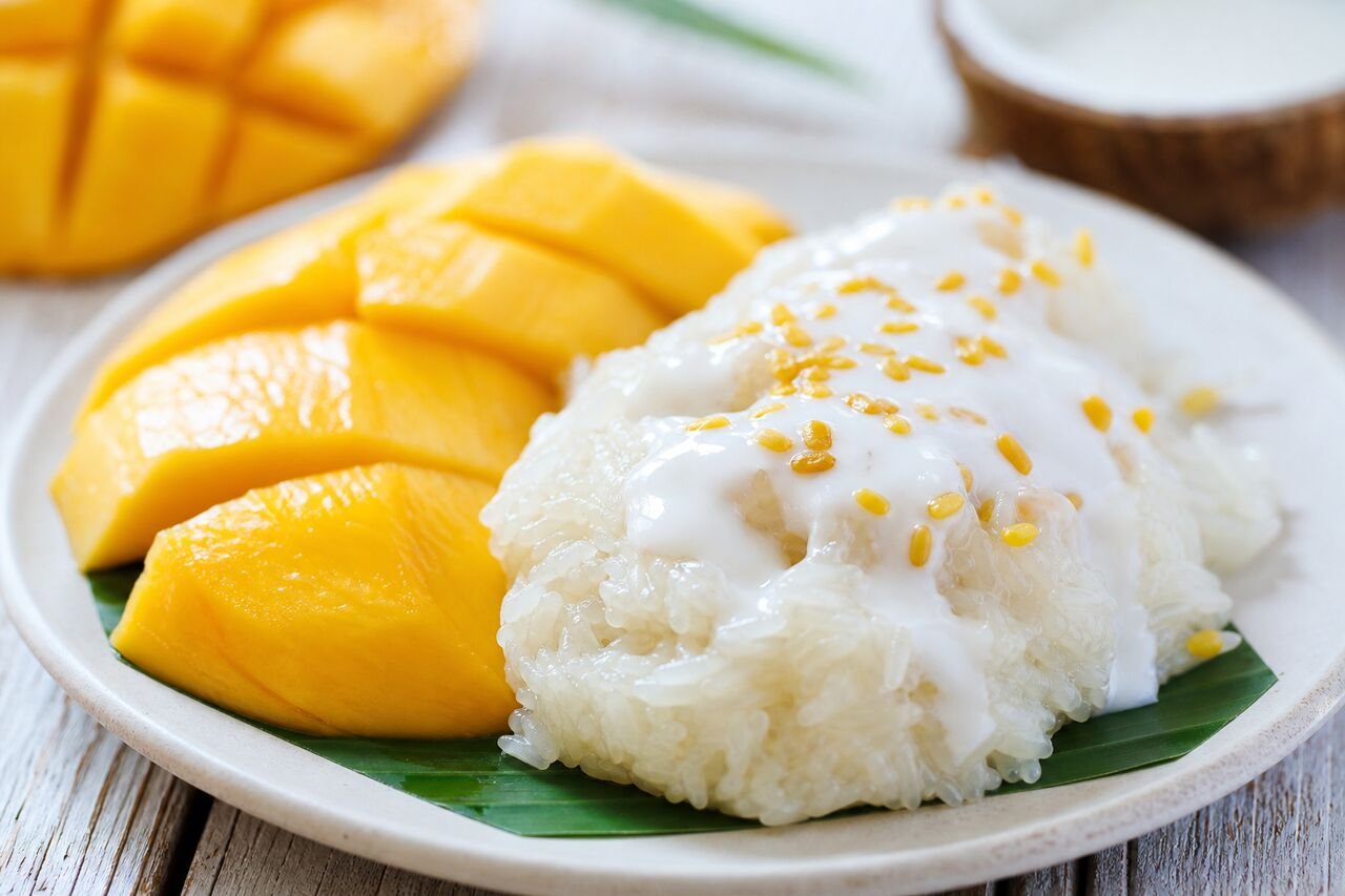 A close serving of Thai Mango Sticky Rice with coconut cream and toasted mung beans.