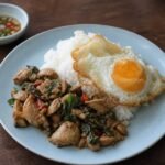 Thai pad kra pao gai with holy basil chicken, jasmine rice, and a fried egg.