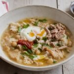 Tunisian lablabi chickpea and bread soup with egg, harissa, tuna, capers, and olive oil.