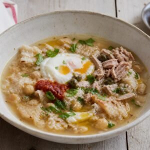 Tunisian lablabi chickpea and bread soup with egg, harissa, tuna, capers, and olive oil.