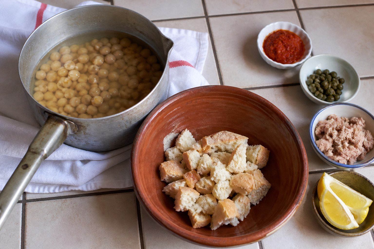 Chickpeas, bread, harissa, tuna, capers, and lemon ready for assembling Tunisian lablabi.