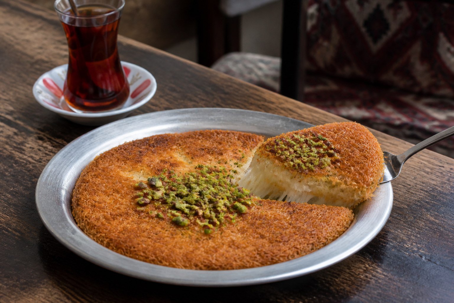 Golden Turkish kunefe with melted cheese and crushed pistachios.