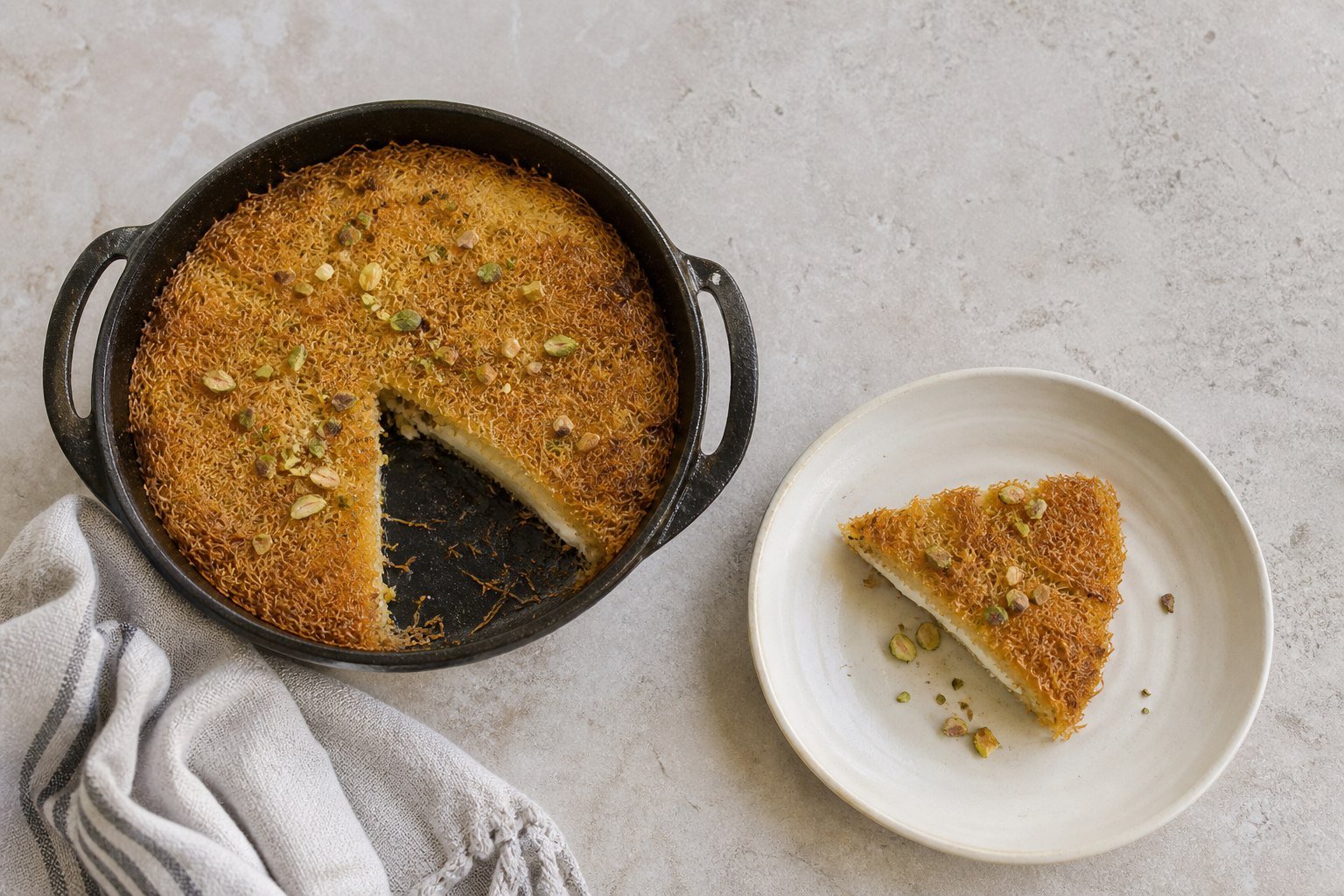A slice of Turkish kunefe beside the baking pan.