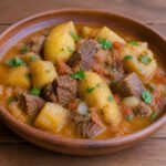 Ugandan matoke stew with tender green banana, beef, tomato, and onion.