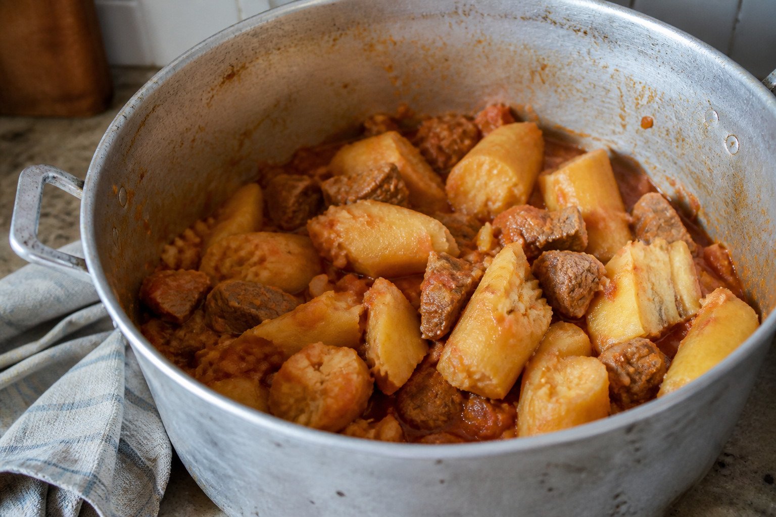 Ugandan matoke cooking in a pot with green banana and beef.