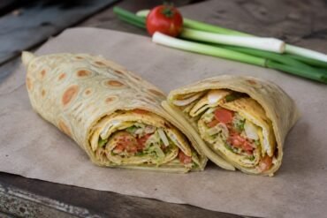 Ugandan rolex chapati wraps cut open to show vegetable omelet filling.