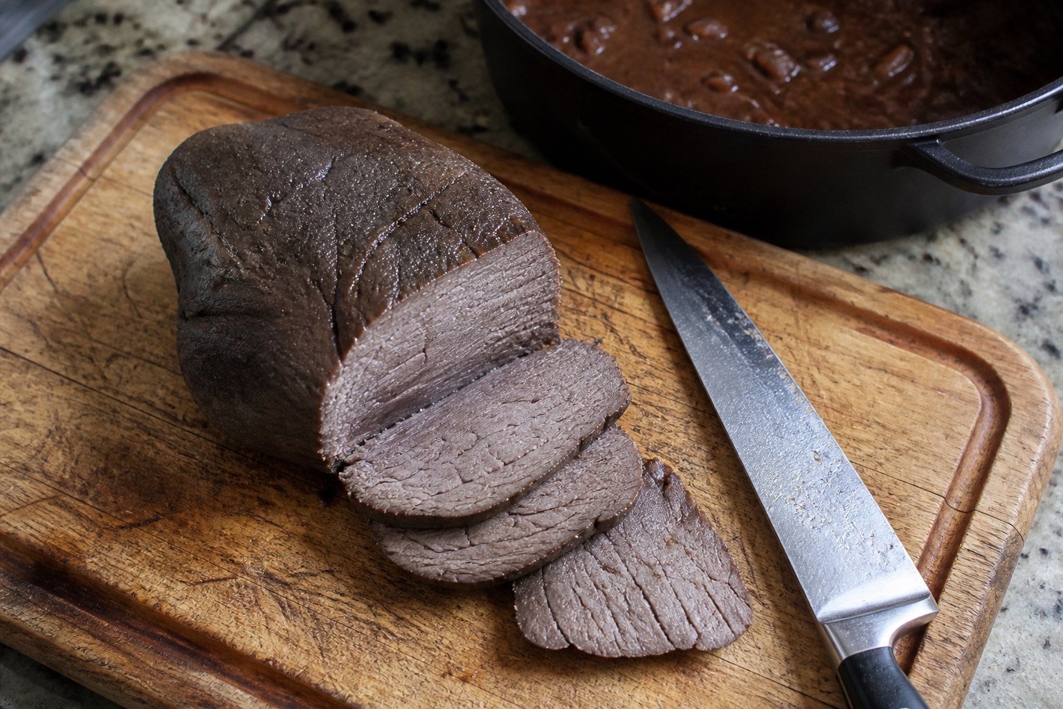 Cooked eye-of-round roast sliced before returning to Venezuelan asado negro sauce.