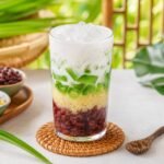 A colorful Vietnamese three-color dessert layered with beans, pandan jelly, coconut milk, and crushed ice.
