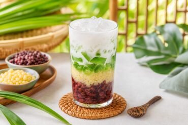 A colorful Vietnamese three-color dessert layered with beans, pandan jelly, coconut milk, and crushed ice.