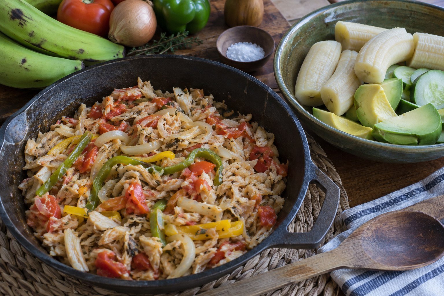 Saltfish with peppers and onions beside boiled green bananas and vegetables.