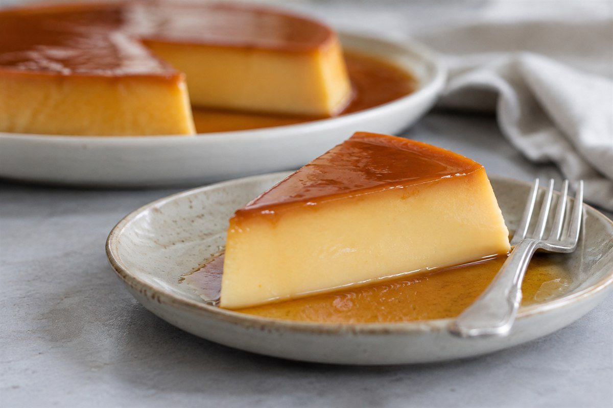 A slice of Filipino leche flan with caramel sauce on a dessert plate.