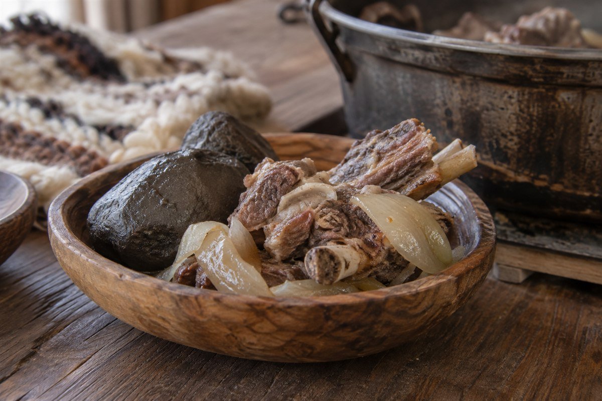 A serving of Mongolian khorkhog with lamb, onion, and a smooth cooking stone.