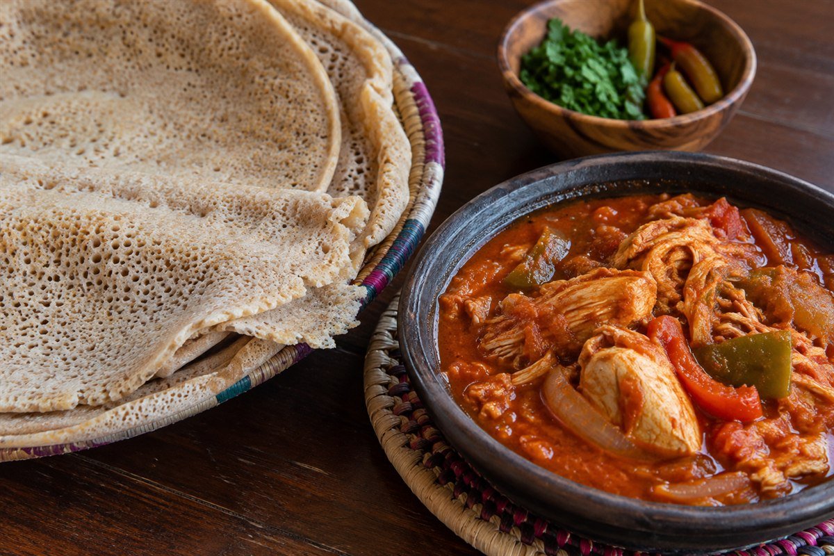 A close serving of soft Somali canjeero with spiced chicken suugo.