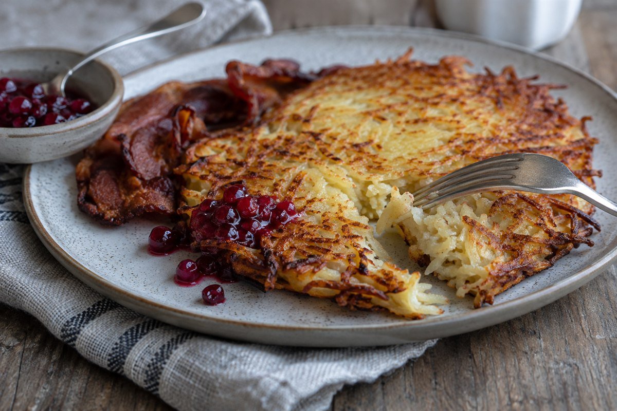 A fork lifting the tender center of a crisp Swedish raggmunk potato pancake.