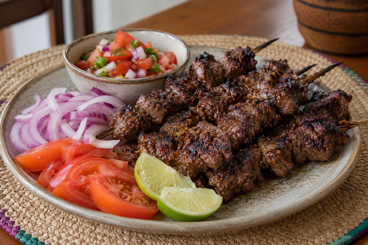 Tanzanian mshikaki beef skewers with kachumbari, tomato, red onion, and lime.
