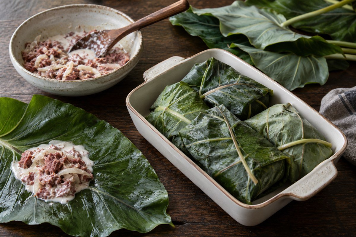 Tongan lu pulu parcels being assembled with taro leaves and corned beef.